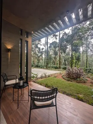 a patio with two chairs and a table and a garden at Earthsong Luxury Pool Villa by Luxunlock Private Villas in Suntikoppa