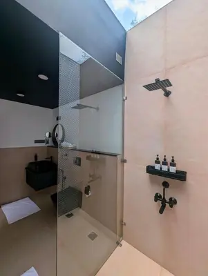 a bathroom with a shower with a glass door at Earthsong Luxury Pool Villa by Luxunlock Private Villas in Suntikoppa