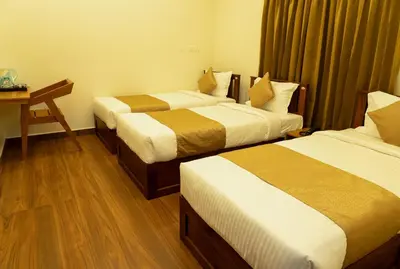 a hotel room with two beds and a desk at FLY VIEW Airport Residency in Nedumbassery