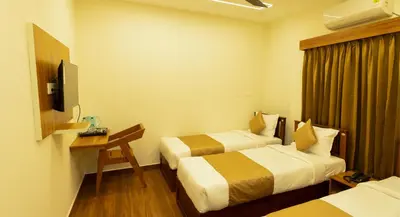 a hotel room with two beds and a television at FLY VIEW Airport Residency in Nedumbassery