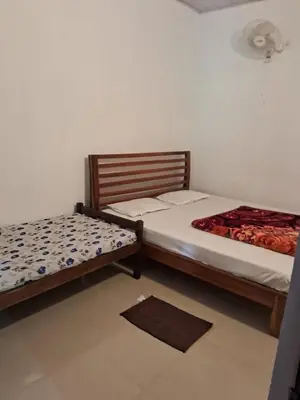 a bedroom with two beds and a rug at Shree Cottage in Madikeri