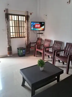 a living room with chairs and a table and a tv at Shree Cottage in Madikeri