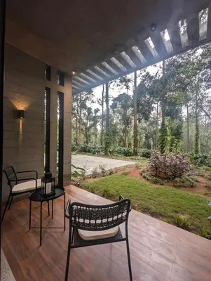 a patio with two chairs and a table with a view of a garden at Earthsong & Birdsong Luxury Pool Villa by Luxunlock Private Villas in Suntikoppa