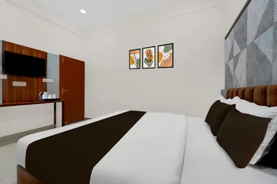 a bedroom with a white bed with a black and white comforter at Townhouse Thondayad Calicut Formerly Dream Casa in Kakkayam