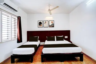 a bedroom with two beds and a window at Super Collection O Rajkumar Road Formerly Stone Villa in Narasimharaja Puram