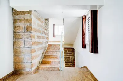 a staircase in a house with a brick wall at Super Collection O Rajkumar Road Formerly Stone Villa in Narasimharaja Puram