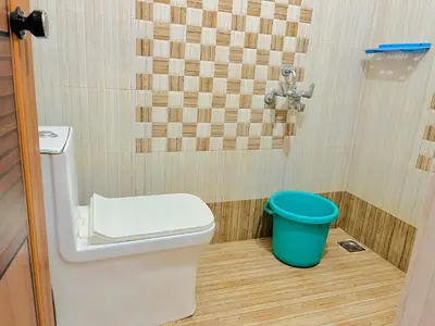 a bathroom with a toilet and a blue bucket at 1 BHK flat in Guruvayur - Sooryamadhavam Apartments-only for pilgrims in Guruvāyūr