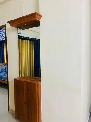 a mirror and a wooden cabinet in a room at 1 BHK flat in Guruvayur - Sooryamadhavam Apartments-only for pilgrims in Guruvāyūr