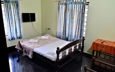 a bedroom with a bed with curtains and a table at Ceema Homestay in Ernakulam