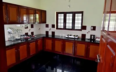 a kitchen with wooden cabinets and black counter tops at Ceema Homestay in Ernakulam
