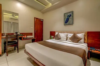 a bedroom with a bed and a desk and a chair at Hotel J N Stay Mysore - 12 Minutes to Mysore Palace in Mysore