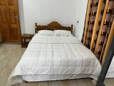 a bedroom with a white bed with a wooden headboard at Serenity Home Stay in Sultan Bathery