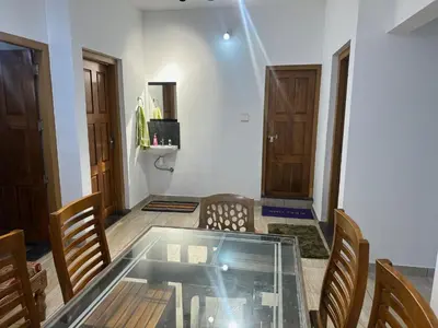 a dining room with a glass table and chairs at Serenity Home Stay in Sultan Bathery