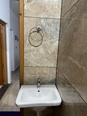 a white sink in a bathroom with a stone wall at Serenity Home Stay in Sultan Bathery
