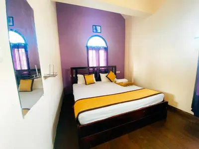a bedroom with a bed with purple walls and two windows at Hilltown Villa Holiday's in Ooty