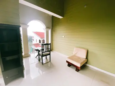 a room with a green wall with a chair at Hilltown Villa Holiday's in Ooty