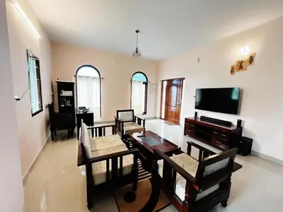 a living room with a table and a television at Hilltown Villa Holiday's in Ooty