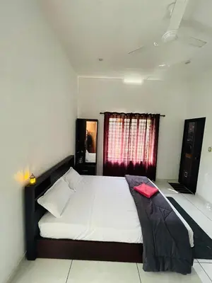 a bedroom with a large white bed with a window at aphrodite home stay in Pinangode