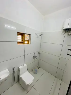 a white bathroom with a toilet and a sink at aphrodite home stay in Pinangode
