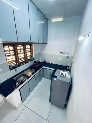 a large kitchen with blue cabinets and a sink at aphrodite home stay in Pinangode