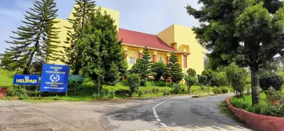 a yellow building on a road next to a tree at The Monarch in Ooty