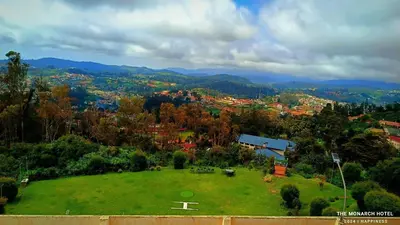 a large green field with a city in the background at The Monarch in Ooty