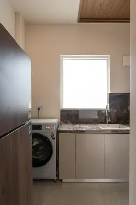 a kitchen with a washing machine and a window at Sanketam Motel in Calicut