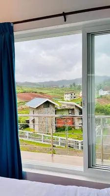a bedroom window with a view of a field at Away From Home - 6 - Rooms In Ooty, Home Stay Ooty in Ooty
