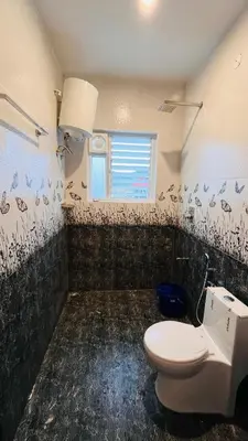 a bathroom with a toilet and a window at Away From Home - 6 - Rooms In Ooty, Home Stay Ooty in Ooty