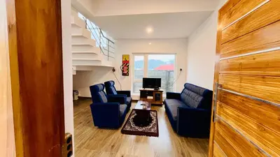 a living room with blue couches and a staircase at Away From Home - 6 - Rooms In Ooty, Home Stay Ooty in Ooty