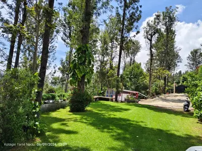 a yard with green grass and trees on a sunny day at May Fair Vista Luxury Villa - Huge Lawn - Scenic Views - Free Parking in Kotagiri