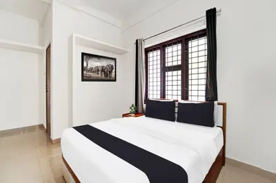 a bedroom with a black and white bed and a window at Super Hotel O West Hill near Mietra Hospital in Calicut