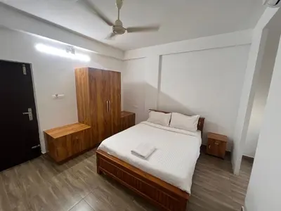 a bedroom with a bed and a wooden cabinet at Ashtapadi Inn in Guruvāyūr