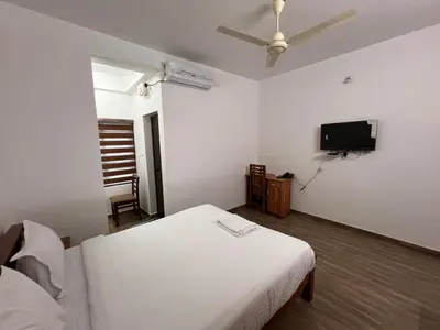 a bedroom with two beds and a flat screen tv at Ashtapadi Inn in Guruvāyūr