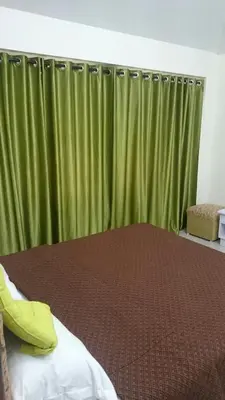 a bedroom with a bed with a green curtain at Ooty Blue Mountain Villa Thalayathimund in Ooty