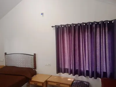 a bedroom with a bed and a purple curtain at Ooty Blue Mountain Villa Thalayathimund in Ooty
