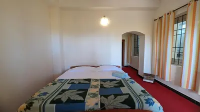 a bedroom with a bed with a quilt on it at Yellow House Kotagiri in Kotagiri