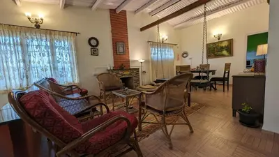 a living room with chairs and a table and a fireplace at Yellow House Kotagiri in Kotagiri