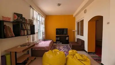 a living room with yellow walls and a table and chairs at Yellow House Kotagiri in Kotagiri