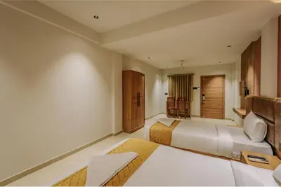 a hotel room with two beds and a table at Hotel Beverly Plaza Kozhikode in Kozhikode