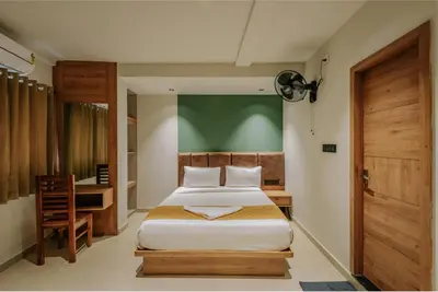 a bedroom with a bed and a desk in it at Hotel Beverly Plaza Kozhikode in Kozhikode