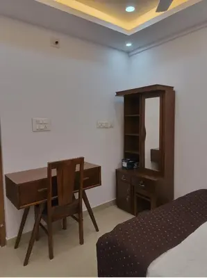 a bedroom with a desk and a bed and a mirror at Posh 1 BHK Apt with Temple View in Guruvayur C1301 in Guruvāyūr