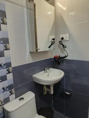 a bathroom with a sink and a toilet and a mirror at Posh 1 BHK Apt with Temple View in Guruvayur C1301 in Guruvāyūr