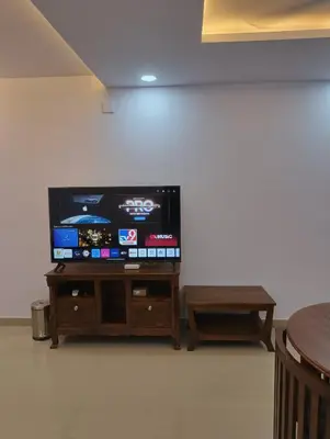 a flat screen tv sitting on top of a wooden stand at Posh 1 BHK Apt with Temple View in Guruvayur C1301 in Guruvāyūr