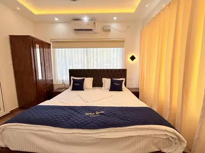 a bedroom with a large bed with blue sheets and a window at Golden Sands Cherai in Cherai Beach