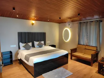 a bedroom with a large bed and a chair at The Cozy Clouds Hill Stay in Napoklu