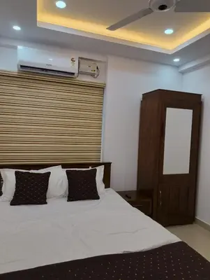 a bedroom with a white bed with a wooden headboard at Posh 1 BHK Apt with Temple View in Guruvayur B1001 in Guruvāyūr