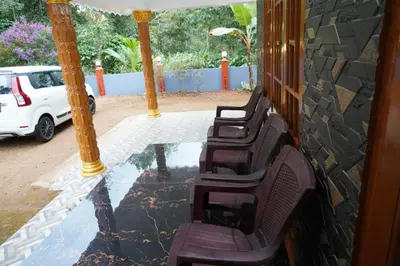 two chairs sitting on a porch with a reflection in the water at Mankulam Holidays Homestay in Viripara