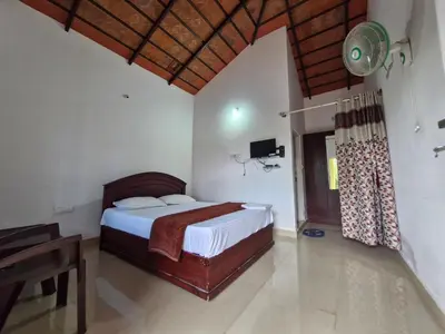a bedroom with a bed and a desk and a television at MAYUR Home Stay in Suntikoppa