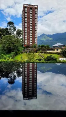 a reflection of a building in a body of water at Aaram Miraj Luxuria Apartment -1 in Wayanad